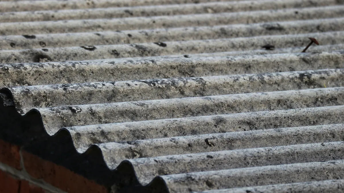 Placas de uralita con amianto de color gris con manchas negras del desgaste y la erosión por el paso del tiempo